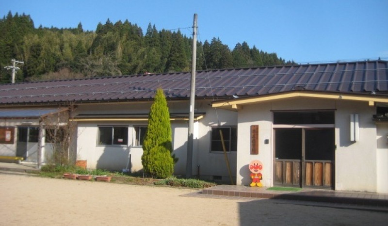 平屋建てで、横に長い園舎の造りで、玄関横にキャラクターの置物が置かれている本庄保育所の外観写真